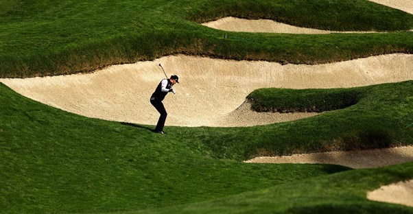 man golfing surrounded by sand pits
