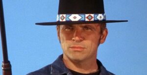 a man wearing a cowboy hat in front of a blue sky