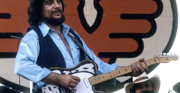 waylon jennings at a concert playing his guitar