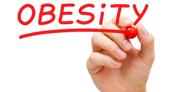 a hand writing the word obesity