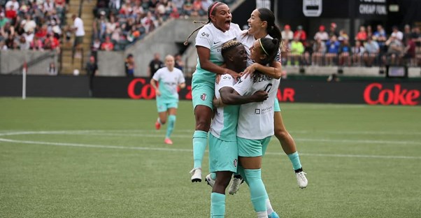 nwsl players celebrate after scoring a goal during a soccer game