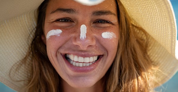 woman at the beach smiling with a sun hat on