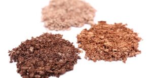 Three piles of crushed makeup containing ingredients you should avoid