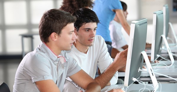 Two young men research careers in electrical engineering on a computer