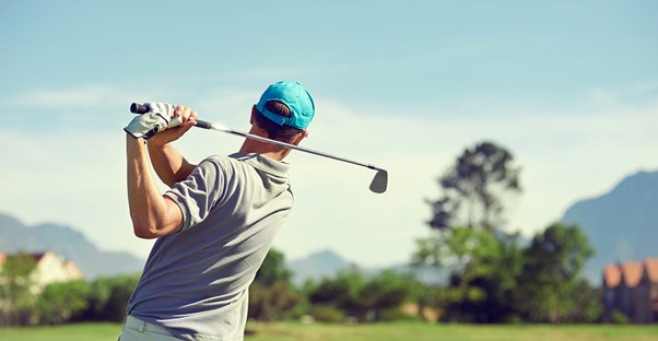 a man driving a golf ball down a fairway