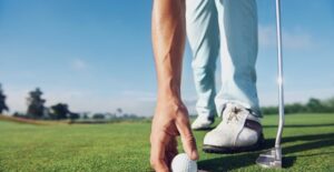 a man placing a golf ball on a putting green