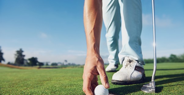 a man placing a golf ball on a putting green