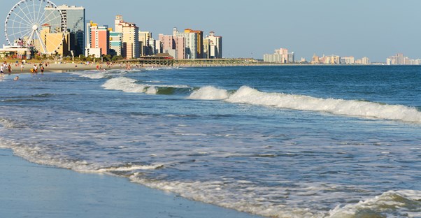 a beachside view of myrtle beach complete with high-rise hotels and a ferris wheel