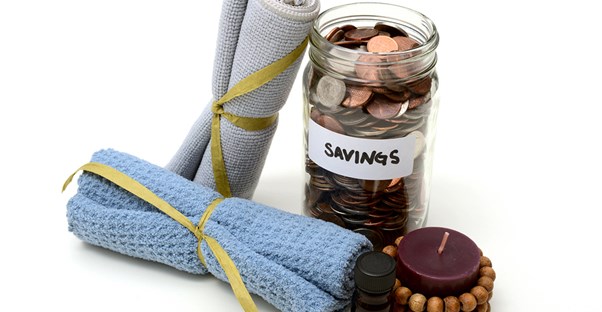 Jar of change sitting next to massage therapy towels and candles to assist with massage therapy school tuition