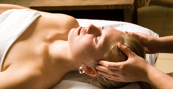 Massage therapy student gives a practice massage to a blonde woman