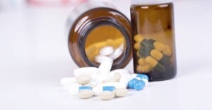 A bottle of blue and white pills spilling out of it lies sideways on a counter.
