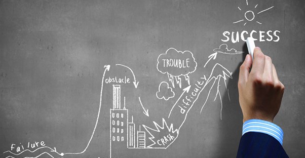 Hand drawing an image on a chalk board to represent the path to successfully starting a business
