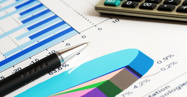 Close up of a pen and calculator sitting on top of an asset management chart