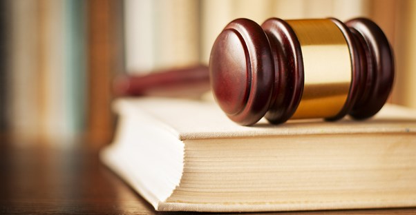 A wooden gavel resting on top of a book containing the questions you should ask an accident injury lawyer