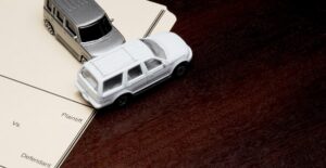 Toy cars in a collision on top of papers on a desk to represent the disadvantages of an accident injury lawyer