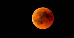 the moon with an orange reddish tint to it in the night sky