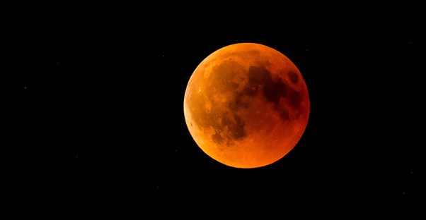 the moon with an orange reddish tint to it in the night sky