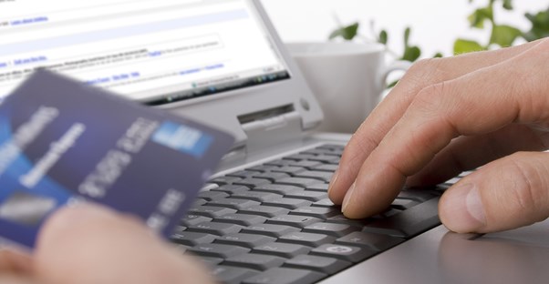Man researching onling about how to be successful using credit card processing while holding a credit card