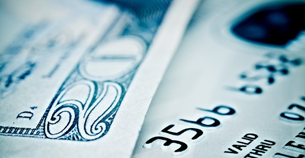 Close up of a twenty dollar bill and a credit to represent the money that can be lost to credit card processing scams.