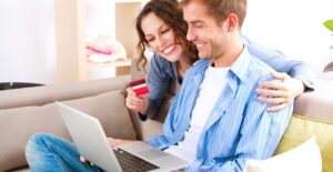 Man and woman smile looking at the best e-commerce website builder on their computer.