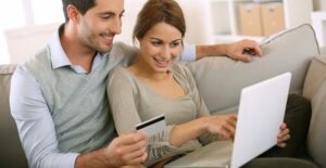 Couple sitting on a couch researching everything they need to know about e-commerce for their online business.