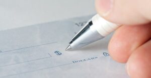 Someone signing a contract agreeing to be a guarantor for a family members loan.