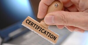 Hand holding a wooden stamp reading certification about to stamp a certificate of deposit agreement.