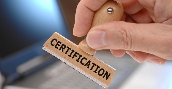 Hand holding a wooden stamp reading certification about to stamp a certificate of deposit agreement.