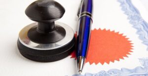 A pen and stamp sitting on the edge of a certificate of deposit agreement to represent the process of certificates of deposit.