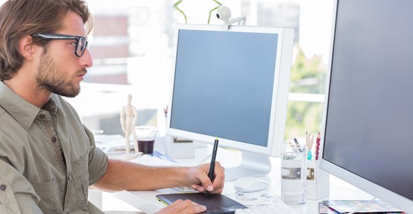 Male graphic designer frowning at his computer as he calculates his salary.