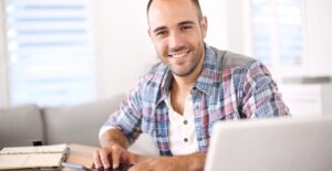 Man smiling as he checks on his online savings account from his computer at home.