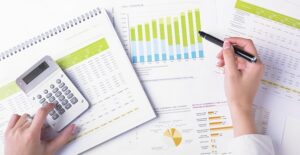 Woman scatters information on the different kinds of mutual funds across her table and calculates which is the right investment for her.