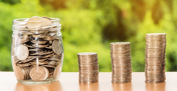 piles of coins next to a jar of money symbolizing a savings account