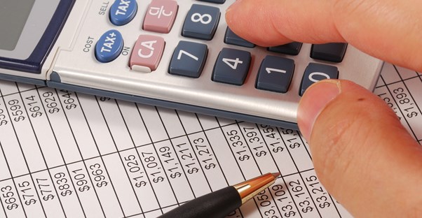 Close up of a man typing numbers into calculator to calculate his mutual funds expense ratio.