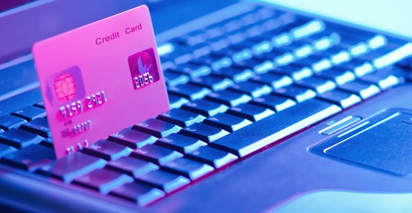 A credit card sitting between the keys of a laptop as someone researches for the advantages of consolidating credit cards.