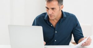 Man searches on his laptop for a credit card consolidation service.
