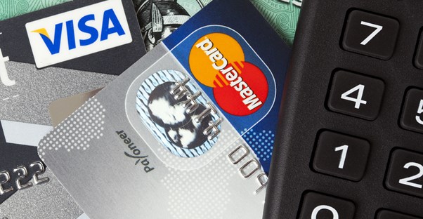 Credit cards sticking out from underneath a calculator being used by a client of one of the best credit card consolidation companies.