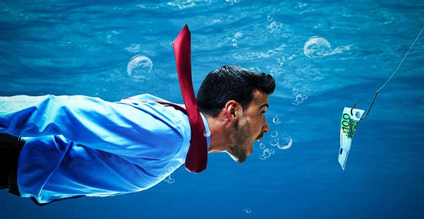 a business man underwater is being tempted by money on the end of a fishing line