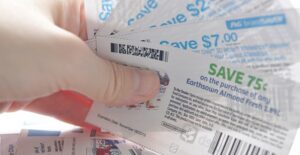 A fan of coupons being held while a woman contemplates the disadvantages of couponing.