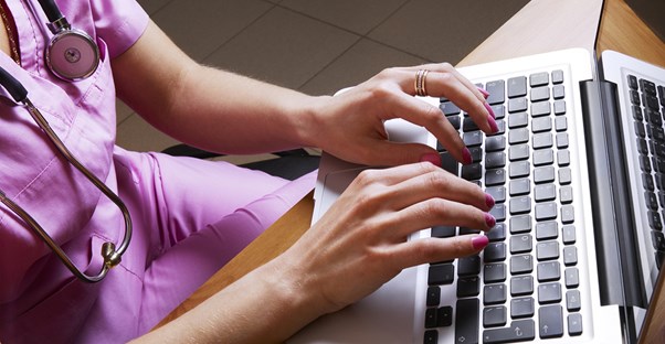 a medical transcriptionist types up a report on a laptop