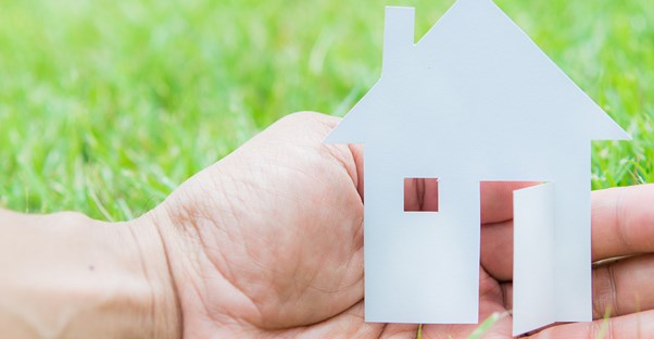 Man holds a paper cut out of a house as he contemplates the disadvantages of home loans.