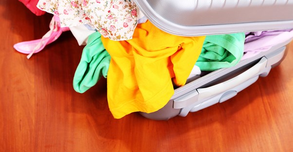 wrinkled clothes stuffed into an overflowing suitcase