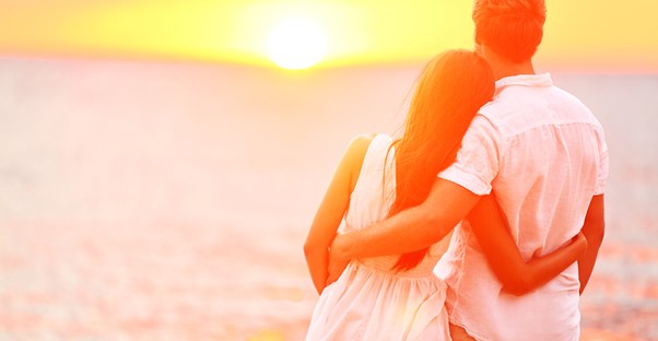 a couple embraces in front of a sunset