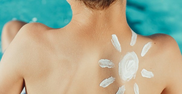 a child rubs sunscreen on his stomace