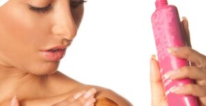 a woman rubs sunless tanning lotion into her skin