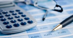 A pen and calculator sitting on top of financial documents as someone calculates their Social Security benefits.