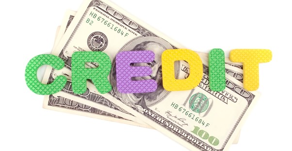 Foam letters spelling Credit laying over a stack of $100 bills earned from the child tax credit.