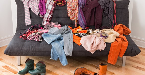 a futon is covered in spare clothing articles
