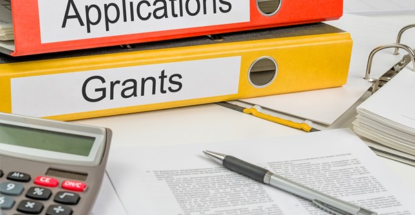 Folders for grants and applications piled on a desk next to other documents need to qualify for the Pell Grant and it's advantages.