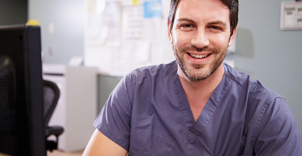 A new nurse practitioner smiles because he has finished his training and is now licensed.